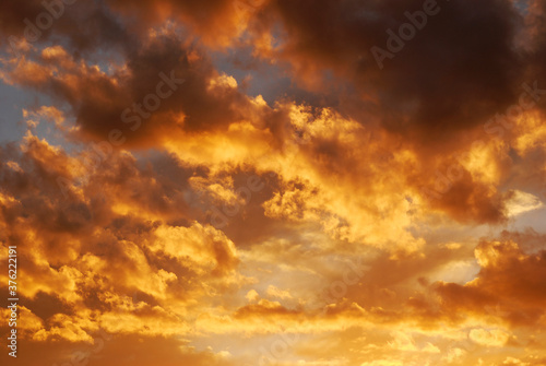 Fire sky background. Soft clouds with the hint of the sun at sunset. Many orange tones and patterns of clouds. © Digihelion