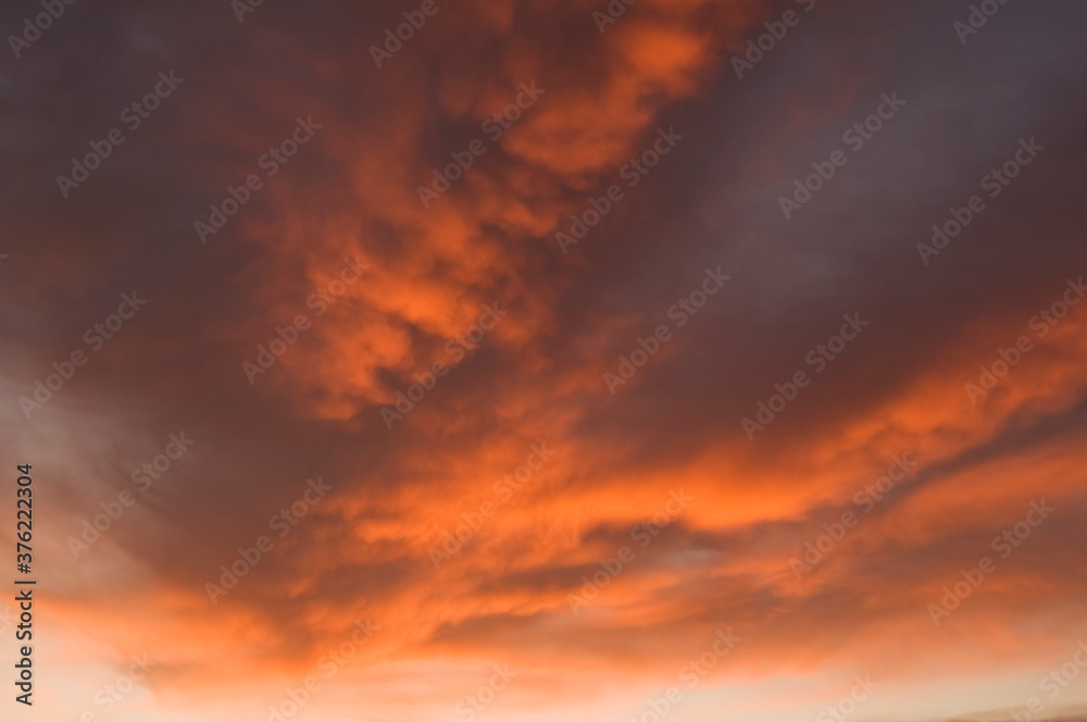 Fire sky background. Soft clouds with the hint of the sun at sunset. Many orange tones and patterns of clouds