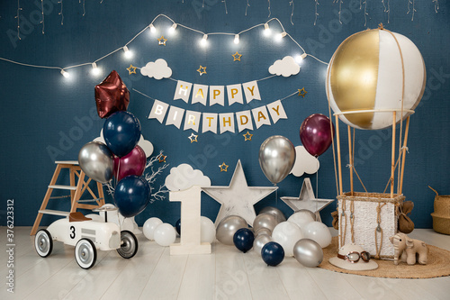 Birthday decorations - gifts, toys, balloons, garland and figure for little baby party on a blue wall background.