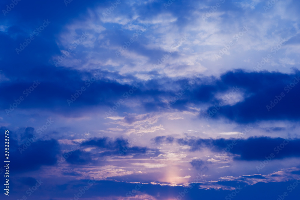Night blue sky and moonlight background. The magic moon shines in the night sky through dark blue clouds.