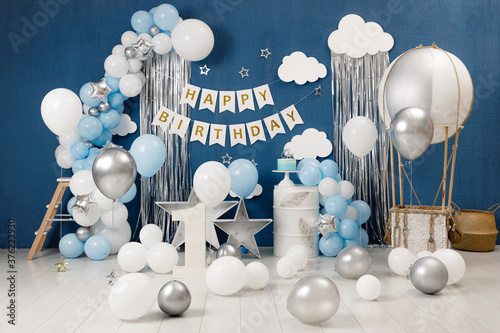 Birthday decorations - gifts, toys, balloons, garland and figure for little baby party on a blue wall background.