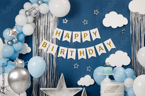 Birthday decorations - gifts, toys, balloons, garland and figure for little baby party on a blue wall background. photo