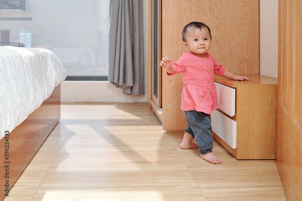 Smiling adorable little girl exploring apartment and walking in bedroom of her parents Smiling adorable little girl exploring apartment and walking in bedroom of her parents