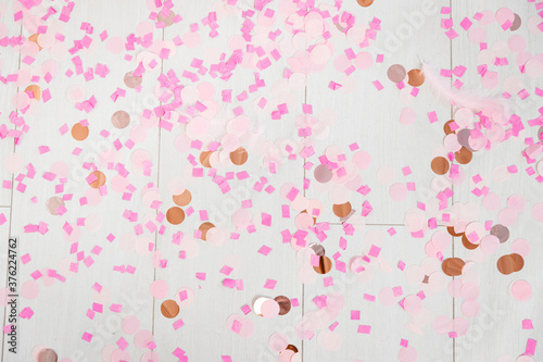 Pink, powder, rose, gold confetti on a wooden white floor background. photo