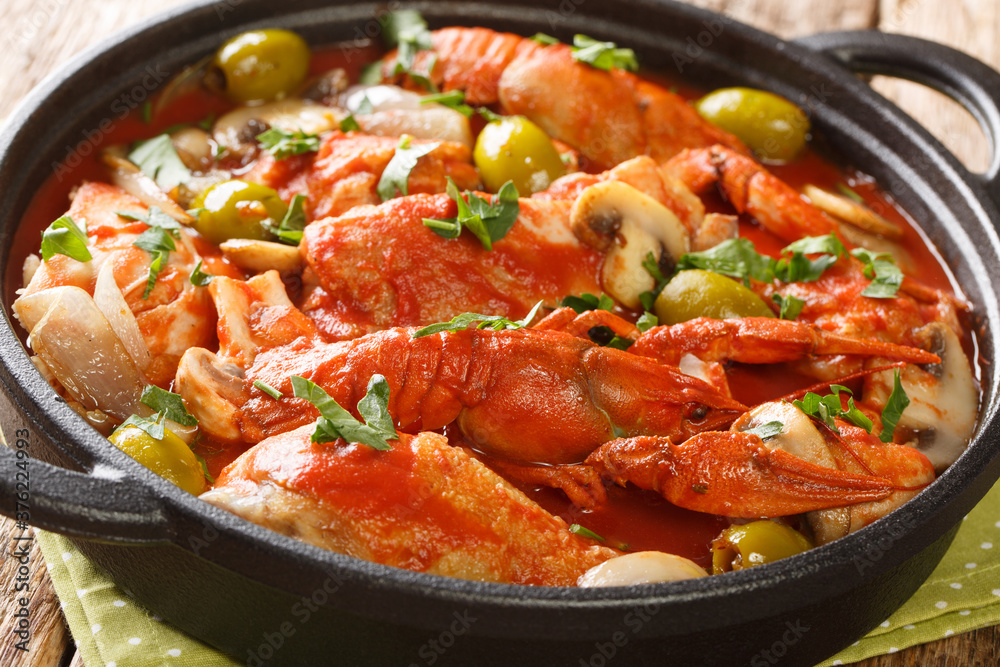 Chicken Marengo cooked with crayfish, mushrooms, olives and shallots in a spicy tomato sauce close-up in a pan on the table. horizontal Chicken Marengo cooked with crayfish, mushrooms, olives and shallots in a spicy tomato sauce close-up in a pan on the table. horizontal