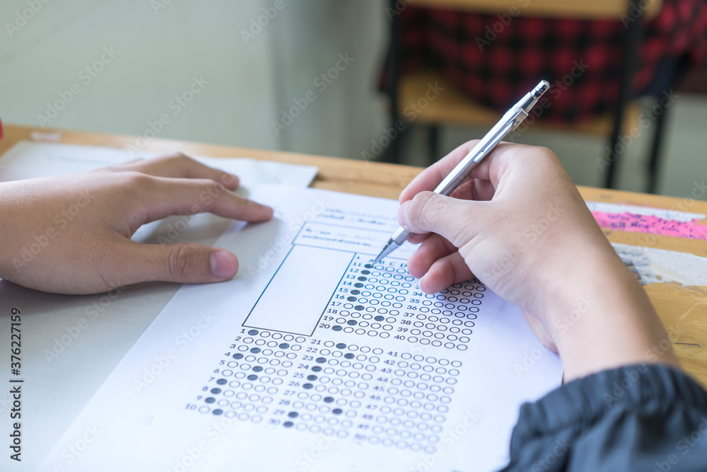 Evaluation or measurement concept. Student testing in exercise taking fill in exam at school or university in test room, writing document exams paper at campus classroom, education back to school idea Evaluation or measurement concept. Student testing in exercise taking fill in exam at school or university in test room, writing document exams paper at campus classroom, education back to school idea