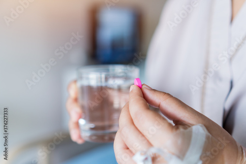 Patient eating medication to treat disease, holding pill tablet and glass of water in hands for taking medicine, Covid-19 virus supplements antibiotic painkiller to relieve pain,revent virus spreading