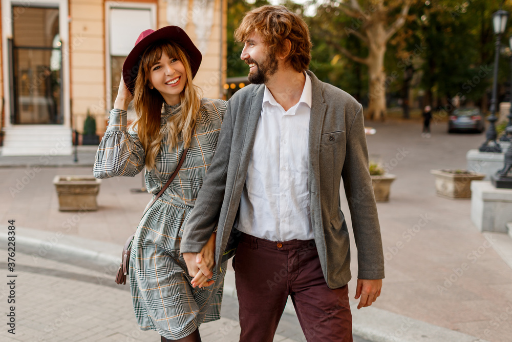 Attractive fashion couple posing on the old street in sunny spring. Pretty beautiful woman and her handsome stylish boyfriend hugging outdoor. Attractive fashion couple posing on the old street in sunny spring. Pretty beautiful woman and her handsome stylish boyfriend hugging outdoor.