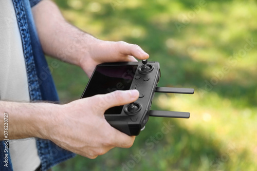 Man holding new modern drone controller outdoors, closeup of hands