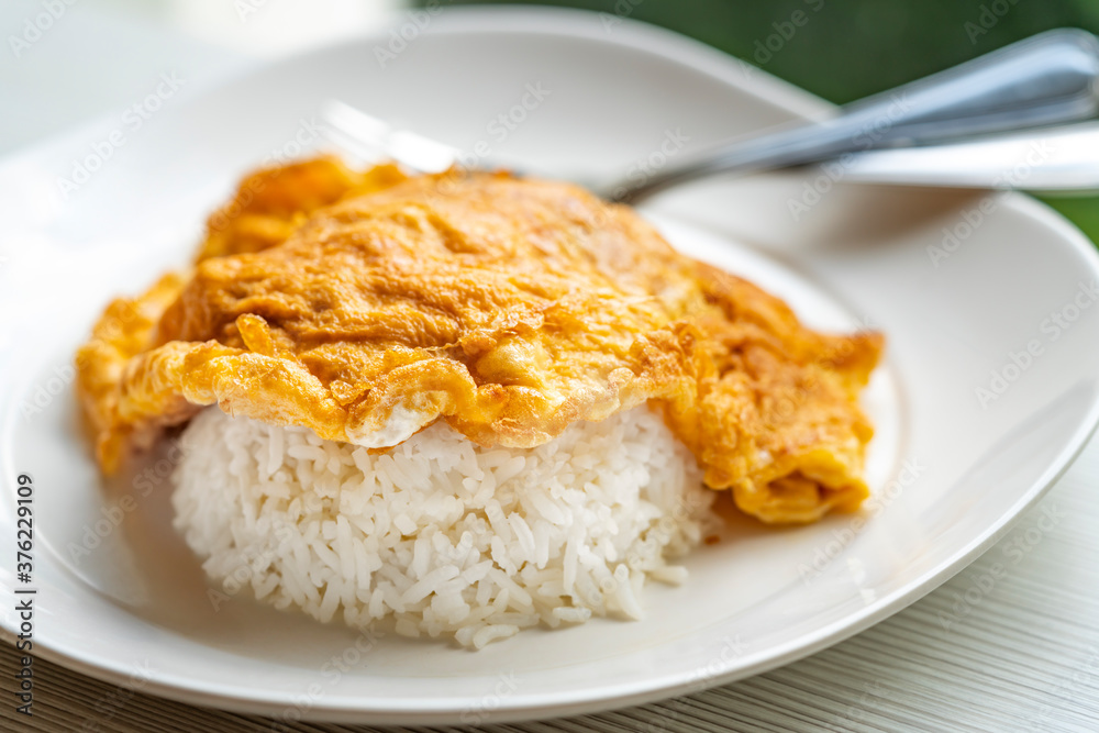 Easy Thai food menu, Thai omelette over rice or Kai Jeaw Rad Kow. Close up Thai omelette over white rice in white plate on table. Easy Thai food menu, Thai omelette over rice or Kai Jeaw Rad Kow. Close up Thai omelette over white rice in white plate on table.