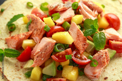 Salmon fish tacos with mango, avocado, tomato, spring onion and lime. Mexican food