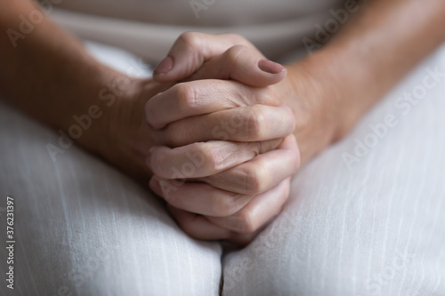 Close up lonely frustrated mature senior woman folded hands on knees together, sitting alone, health or emotional problem, unhappy aged female feeling desperate and depressed, lost in thoughts