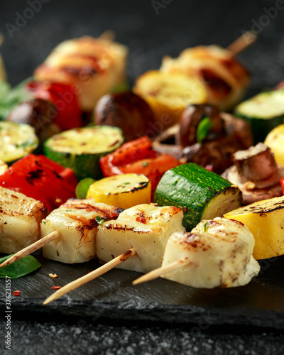 Grilled Halloumi cheese skewers with vegetables on rustic stone board