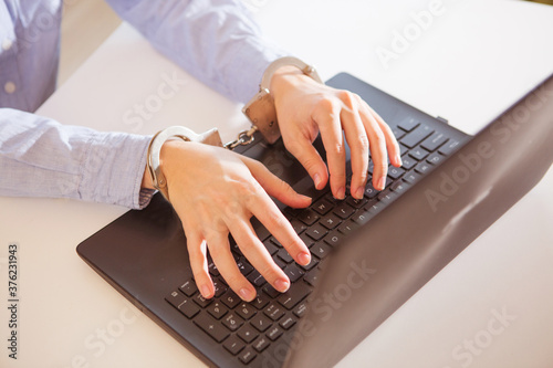 Woman hands locked to laptop by chain on keyboard of notebook photo