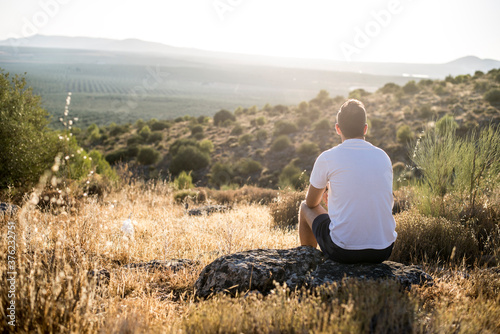 Photos Persona sentada en una piedra en el campo mirando al horizonte y disfrutando de la naturaleza