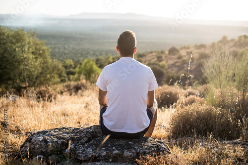 Tableau sur toile Persona sentada en una piedra en el campo mirando al horizonte y disfrutando de la naturaleza