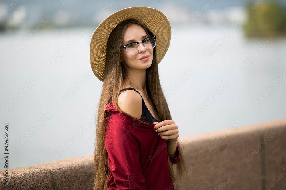 Portrait of an urban woman in a hat and glasses with bare shoulders. Long brown hair. The concept of fashionable stylish clothes. Copycpase