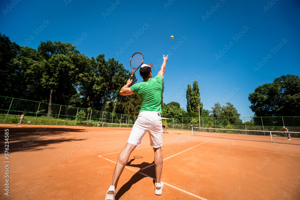 Young athletic man playing tennis on the court.
