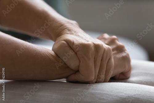 Close up unhappy depressed mature woman sitting on couch alone, feeling desperate and depressed, wrinkled female hands folded on laps, health or emotional problem concept, mental disorder