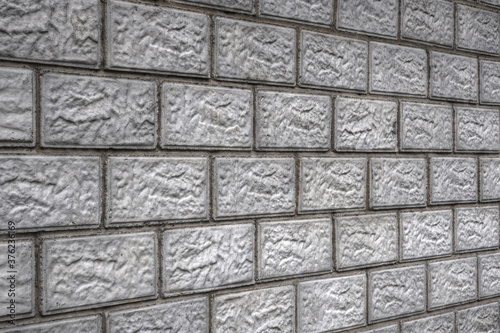 Aged background or wallpaper on a construction theme. The wall of the house is made of gray concrete blocks. Masonry seams provide perspective. Dark backdrop on home renovation