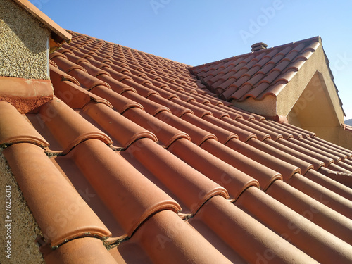 Tiles on the roof of a residential building attic over blue sky