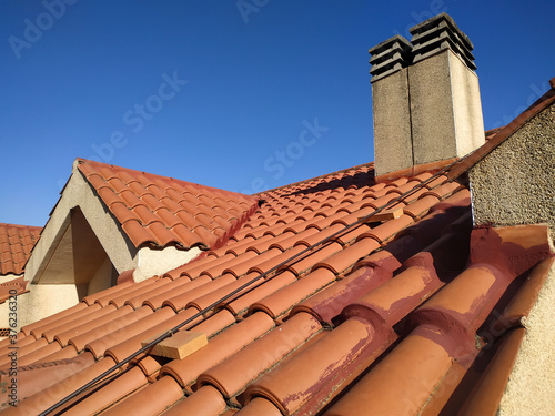 Tiles and chimney on the roof of a residential building attic over blue sky
