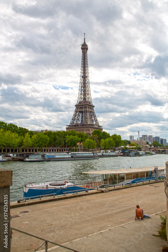 Paris, France. 2019, August. The Seine river with boats and the Eiffel tower in the background during a cloudy summer day,