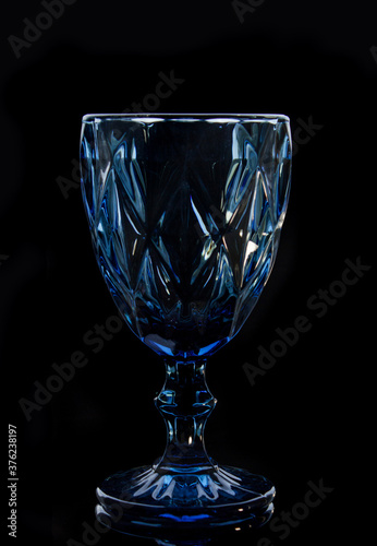 Blue faceted wine glass on black background, close up