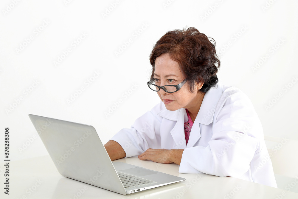 Elderly asian Chinese female doctor on white background wearing white apron notebook computer work browse serous look Elderly asian Chinese female doctor on white background wearing white apron notebook computer work browse serous look