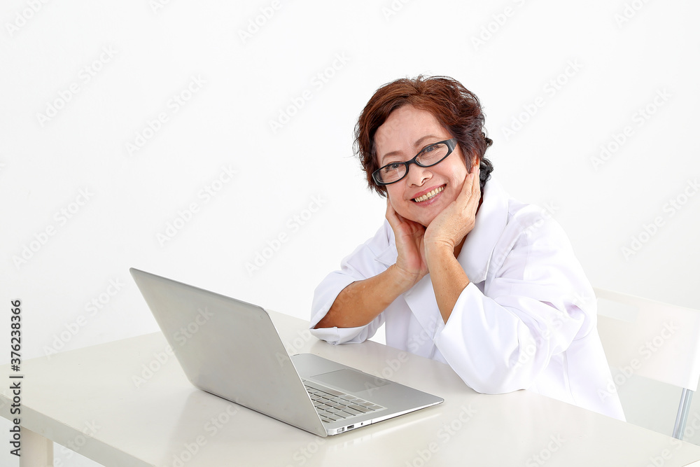 Elderly asian Chinese female doctor on white background wearing white apron notebook computer hand on cheek happy look at camera Elderly asian Chinese female doctor on white background wearing white apron notebook computer hand on cheek happy look at camera