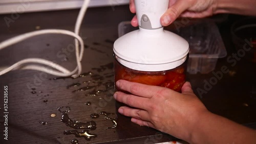 Woman is preparing tomato sauce in blender.