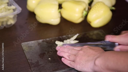 Female hands cut a yellow pepper.