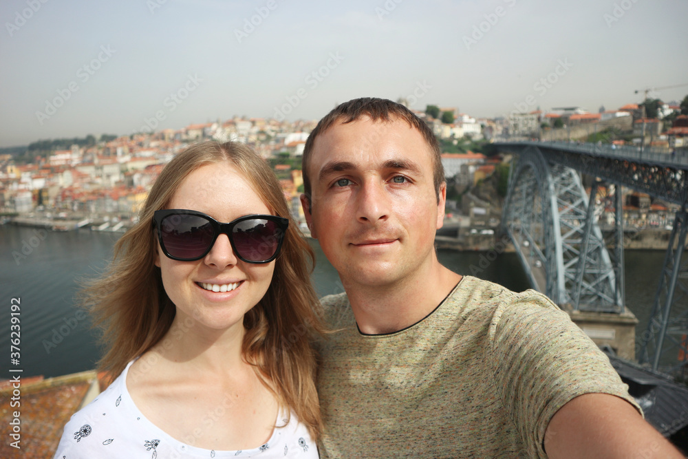 Happy smiling couple of tourists taking selfie photo in Oporto.