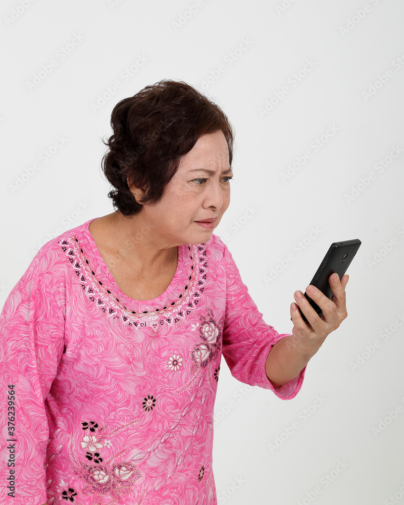 Elderly asian Chinese female on white background read text massage on phone serous look close Elderly asian Chinese female on white background read text massage on phone serous look close