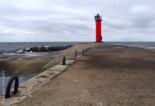 Red lighthouse on the background of the blue sea, the road to the beacon