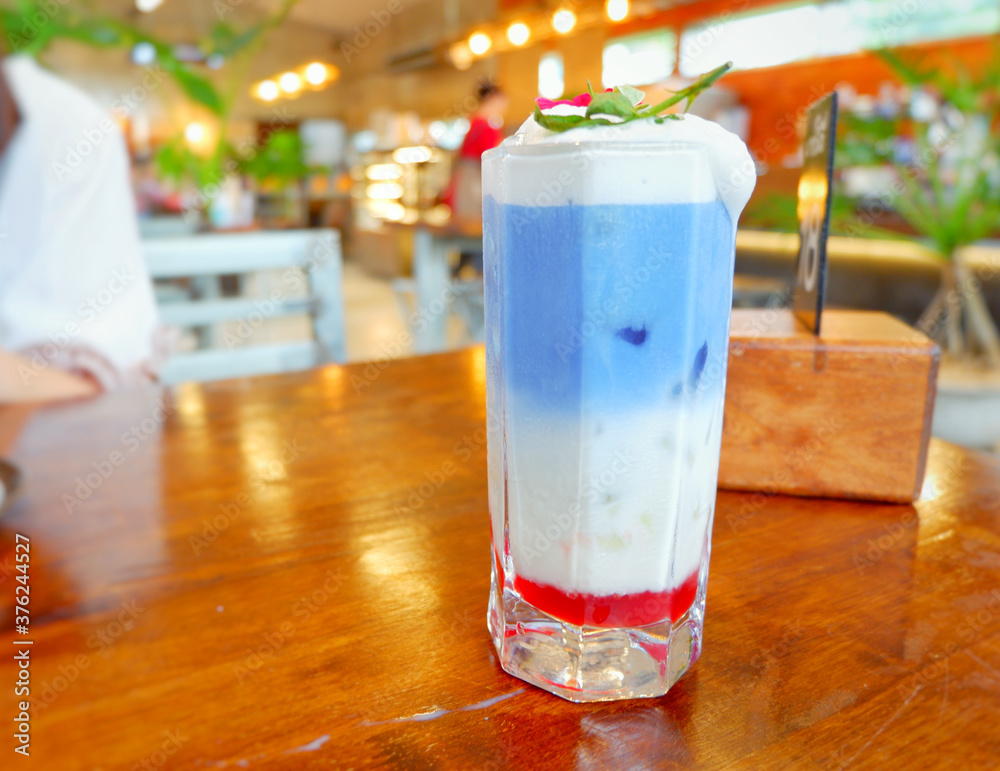 Fresh blue milk juice over coconut milk with ice in glass on wood table. The blue milk is popular menu for order. The taste is delicious. Close up.