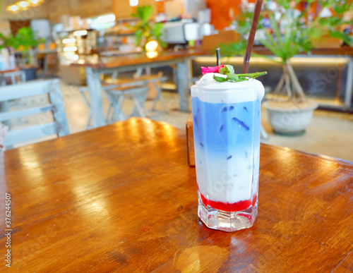 Fresh blue milk juice over coconut milk with ice in glass on wood table. The blue milk is popular menu for order. The taste is delicious. Close up.