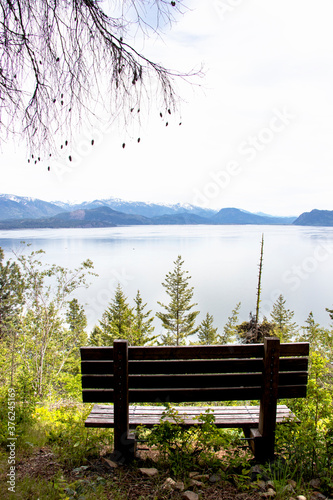 An empty bench overlooking a forested mountain lake. Sit here for pondering life or just enjoying the view. 