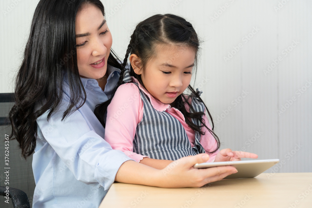 asian mother teach her young daughter to study from tablet at home. homeschooling and family together concept asian mother teach her young daughter to study from tablet at home. homeschooling and family together concept
