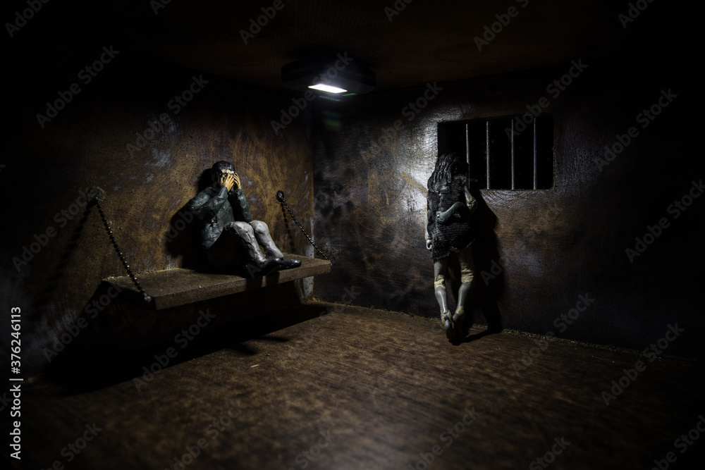 Man in prison man behind bars concept. Old dirty grunge prison miniature. Dark prison interior creative decoration.