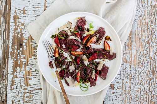 Overhead view of carpaccio and strawberries salad served on plate