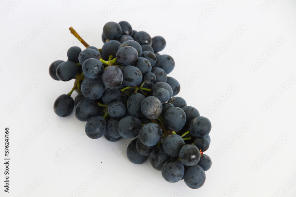 Black grapes, large fresh fruits with green leaves on a white background Black grapes, large fresh fruits with green leaves on a white background