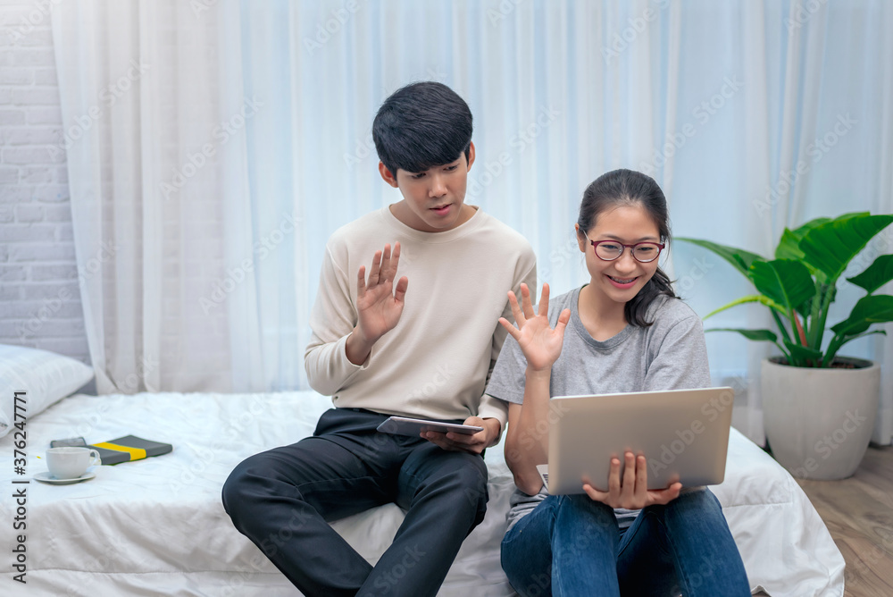 Cheerful two young asian having video call on laptop computer on bed at home. Cheerful two young asian having video call on laptop computer on bed at home.