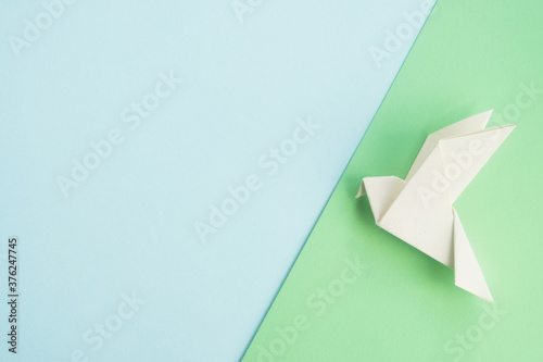 White dove bird origami on pastel background. International day of peace, hope and freedom concept. Mock up for design or greeting card. Top view, copy space