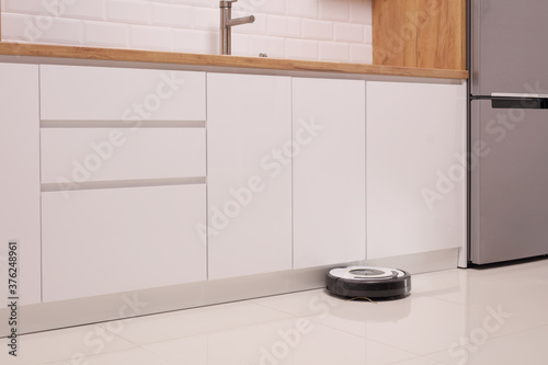 Robot vacuum cleaner on a tiled kitchen floor photo