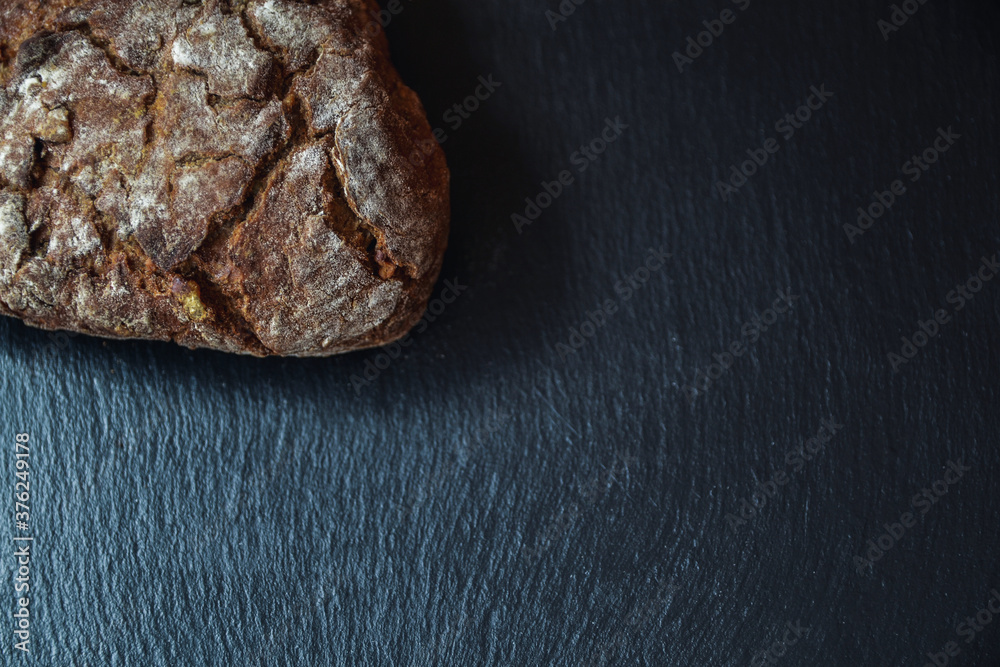 Pan artesano de nueces sobre plato de pizarra negro