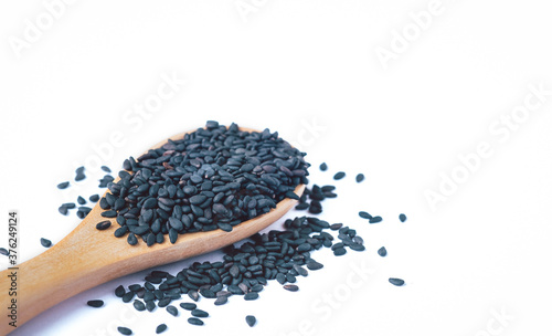 Black sesame seeds in wooden spoon on white background organic food concept