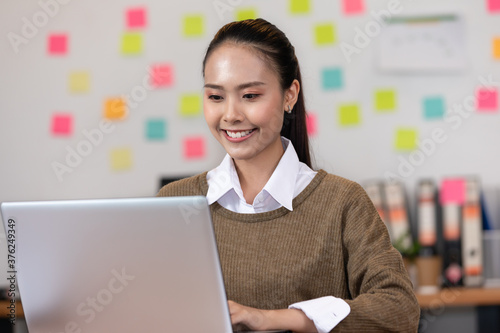 Happy Asian business woman looking laptop working and smile at modern office or Co-Working Space,Business Startup Concept