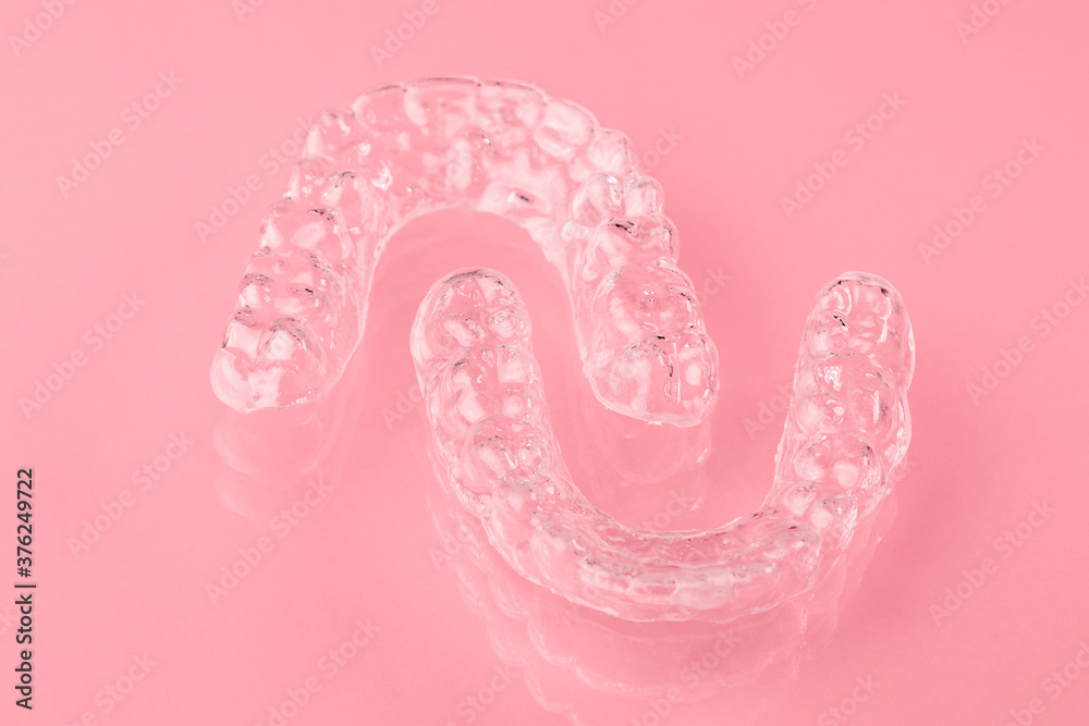 Invisible aligner or retainer for the upper and lower teeth on the pink background. Orthodontic therapy after straightening of teeth. - obrazy, fototapety, plakaty 
