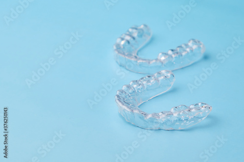 Removable teeth aligners on the blue background with copy space. Orthodontic treatment for beautiful smile.